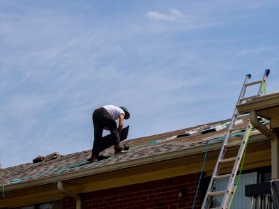 Roof repair, worker with replacing gray tiles shingles on house being applied